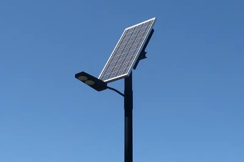 Solar-powered LED street light with its own panel against a clear blue sky
